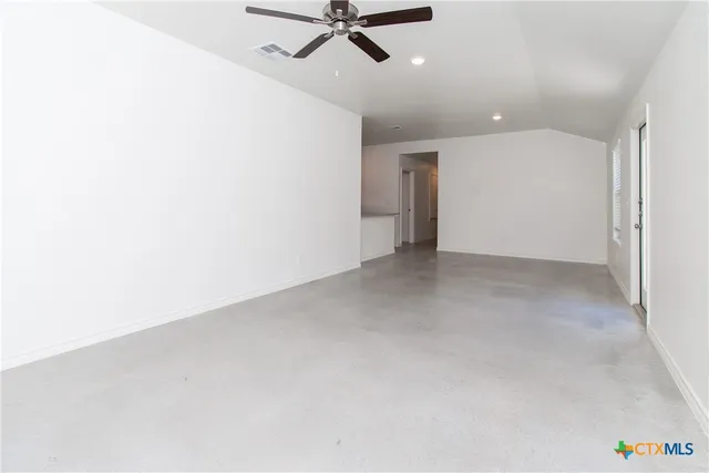 an empty room with a ceiling fan and carpet