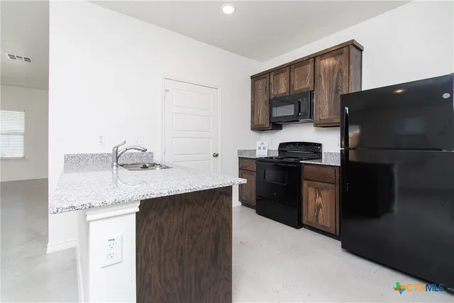 a kitchen with stainless steel appliances granite countertop a refrigerator stove top oven a sink and dishwasher