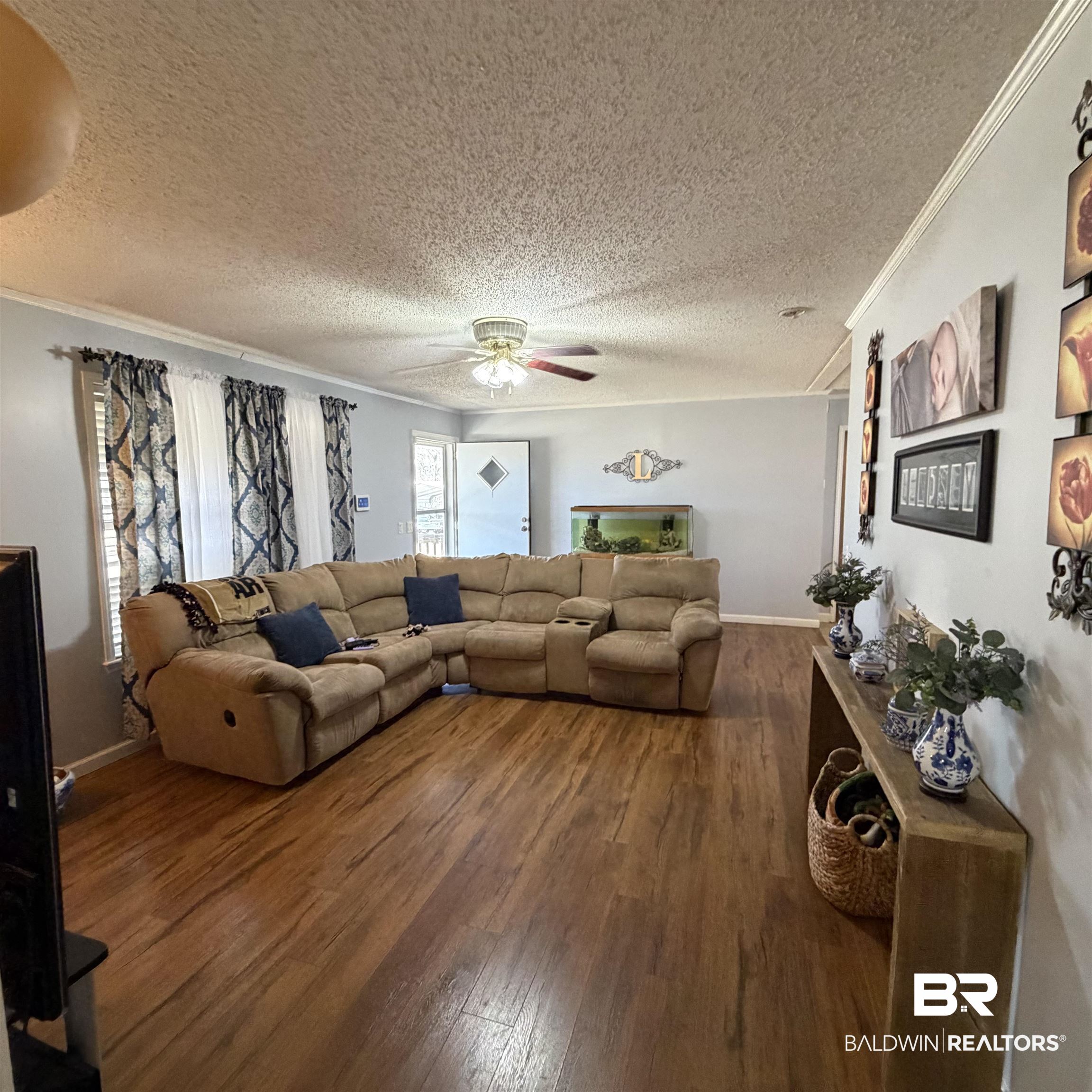 447 Sugar Hill Road Monroeville, AL 36460 - Photo 3 of 27 Living area with dark wood-style flooring, a textured ceiling, a ceiling fan, and ornamental molding
