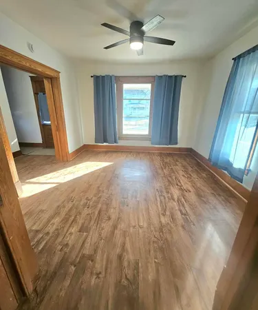 a view of empty room with wooden floor and fan