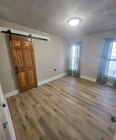 a view of empty room with window and wooden floor