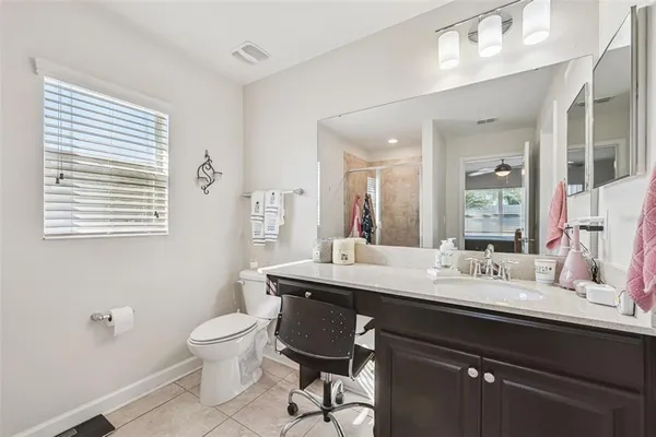 a bathroom with a granite countertop toilet a sink a mirror and a window