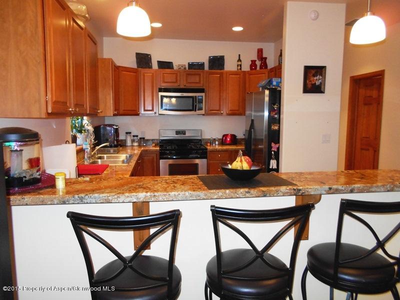 1068 East 17th Street Rifle, CO 81650 - Photo 3 of 9 a kitchen with stainless steel appliances granite countertop a stove top oven a refrigerator a sink and chairs
