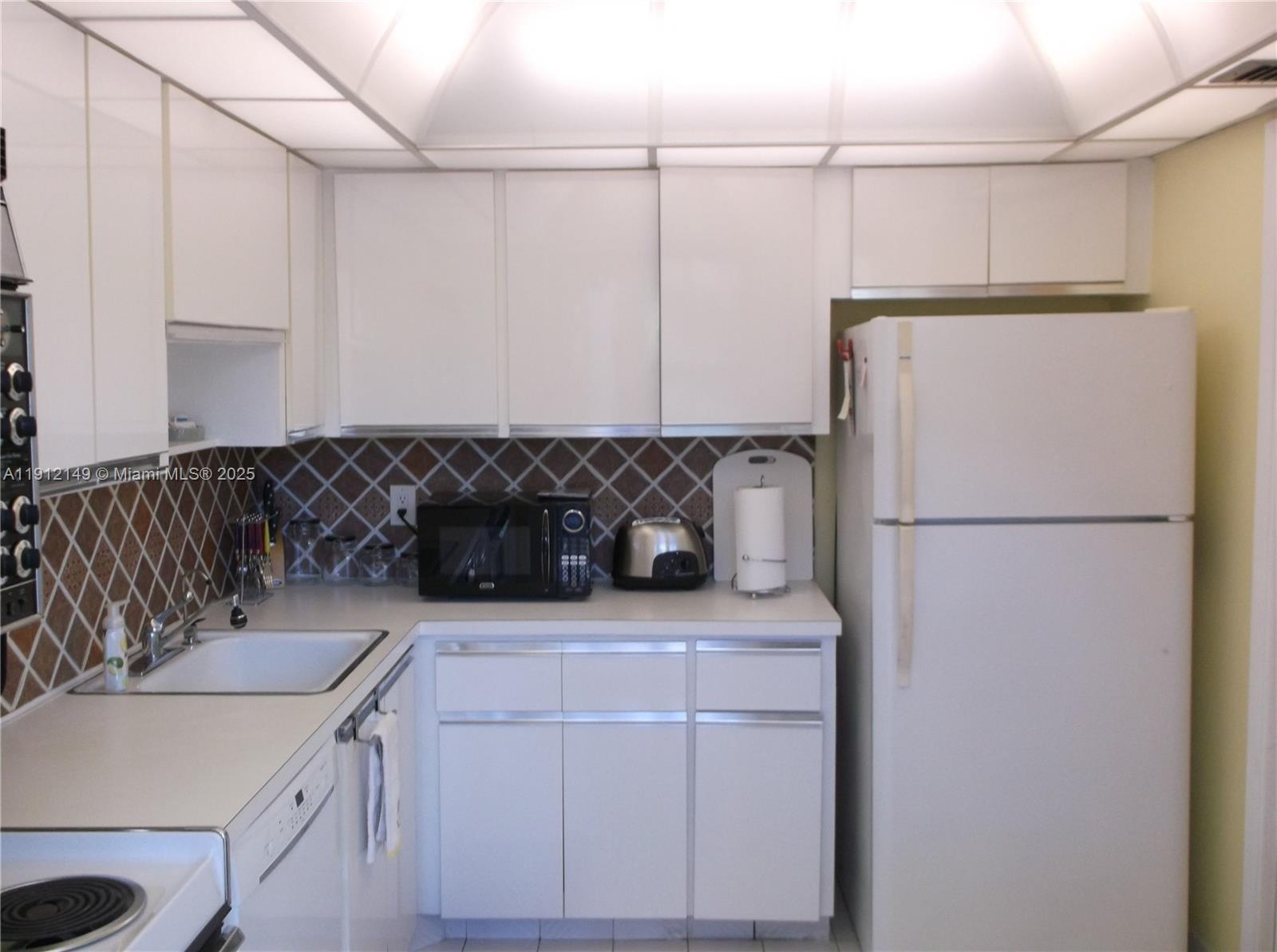 3080 North Course Drive, Unit 209 Pompano Beach, FL 33069 - Photo 15 of 35 a kitchen with a refrigerator and a sink