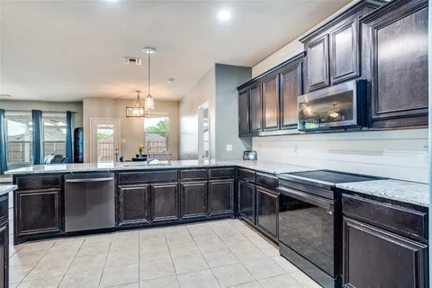a large kitchen with stainless steel appliances granite countertop a stove a sink and a microwave