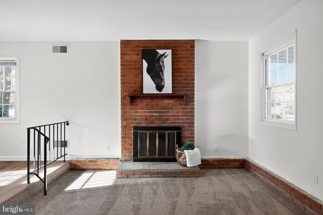 an empty room with windows fireplace and fans