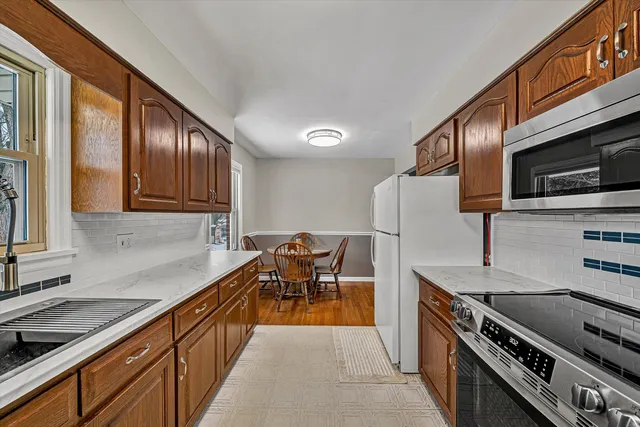 a kitchen with stainless steel appliances granite countertop a stove top oven a sink dishwasher a dining table and chairs with wooden floor