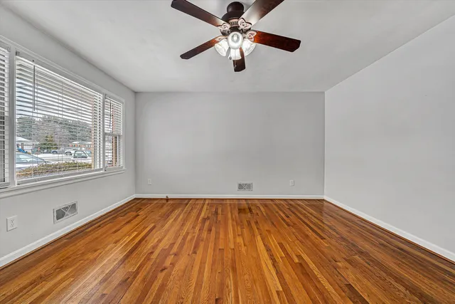 a view of empty room with wooden floor and fan
