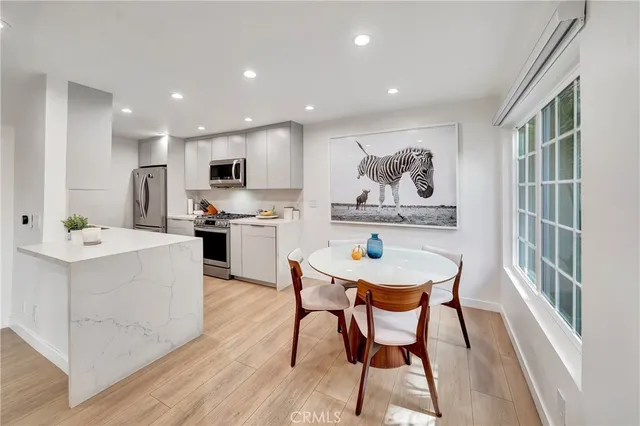 a kitchen with stainless steel appliances kitchen island granite countertop a sink a stove a dining table and chairs