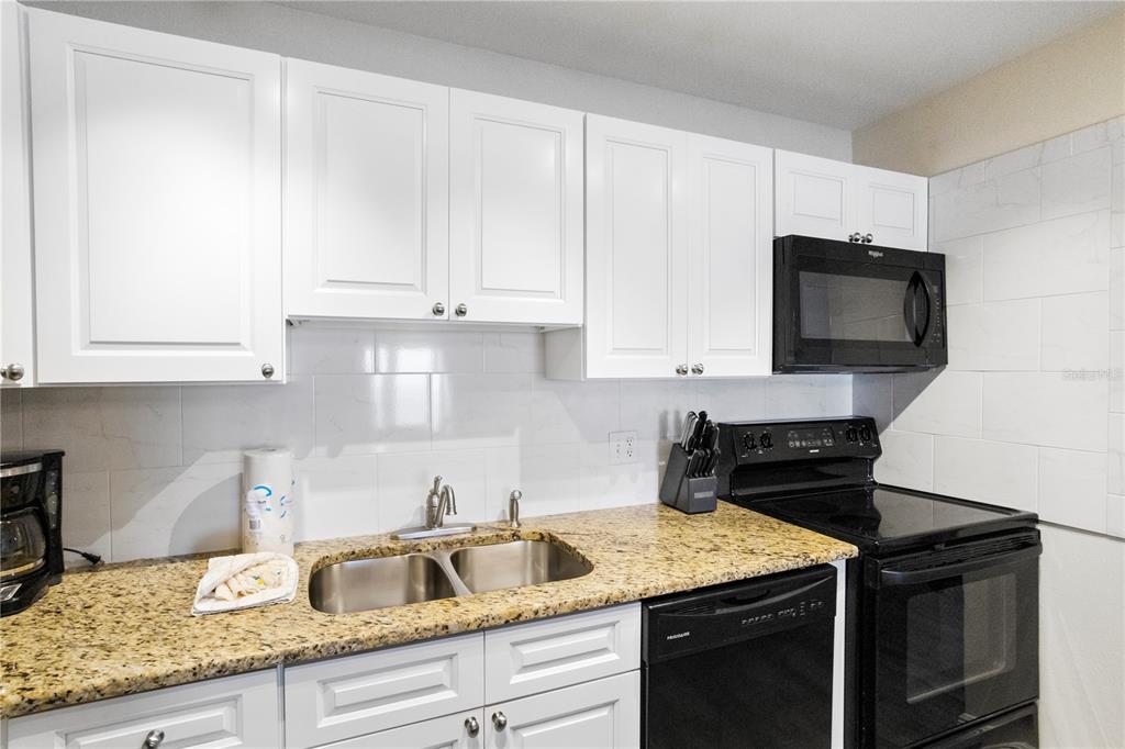 13500 Gulf Boulevard, Unit 505 Madeira Beach, FL 33708 - Photo 14 of 42 a kitchen with granite countertop a stove sink and cabinets