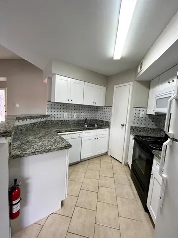 a kitchen with a sink a stove top oven and cabinets