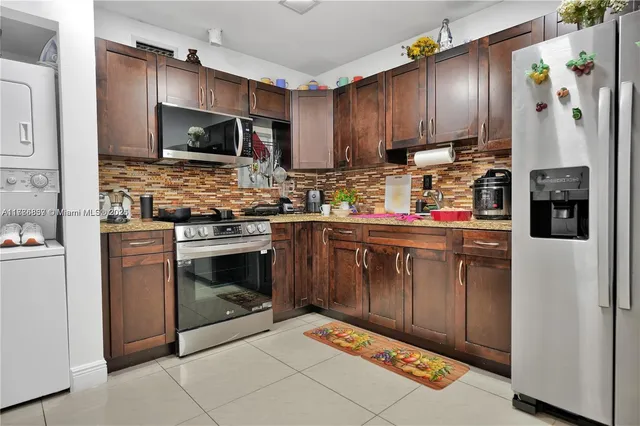 a kitchen with stainless steel appliances granite countertop a stove top oven a refrigerator and a microwave