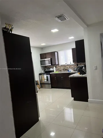 a large kitchen with a sink stainless steel appliances and cabinets