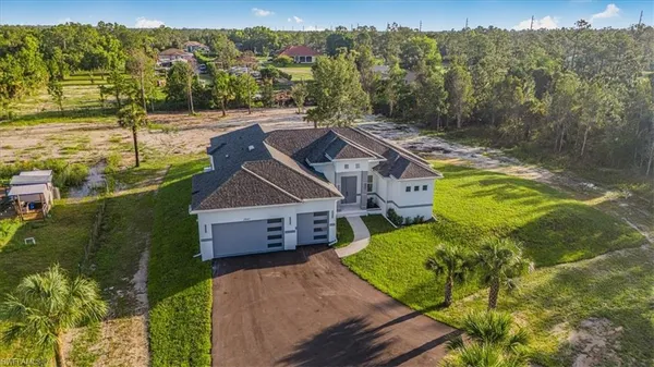 a view of a house with a big yard and large trees