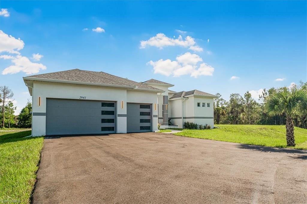 2941 37th Avenue Northeast Naples, FL 34120 - Photo 14 of 46 a front view of a house with a yard and garage
