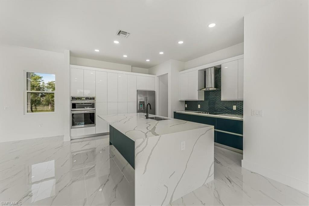 2941 37th Avenue Northeast Naples, FL 34120 - Photo 40 of 46 a kitchen with stainless steel appliances kitchen island granite countertop a refrigerator and a stove top oven