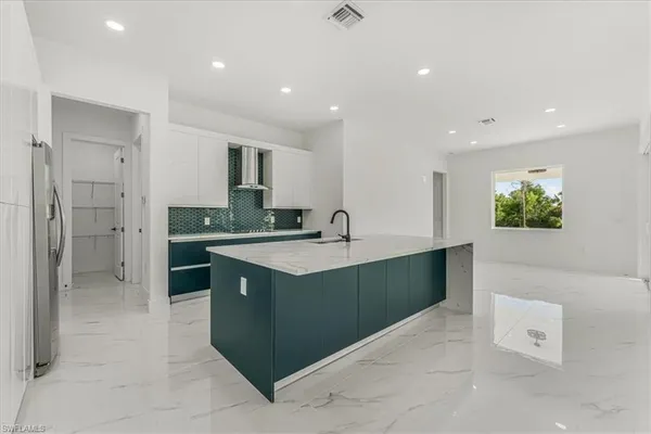 a large kitchen with stainless steel appliances kitchen island granite countertop a refrigerator and a sink