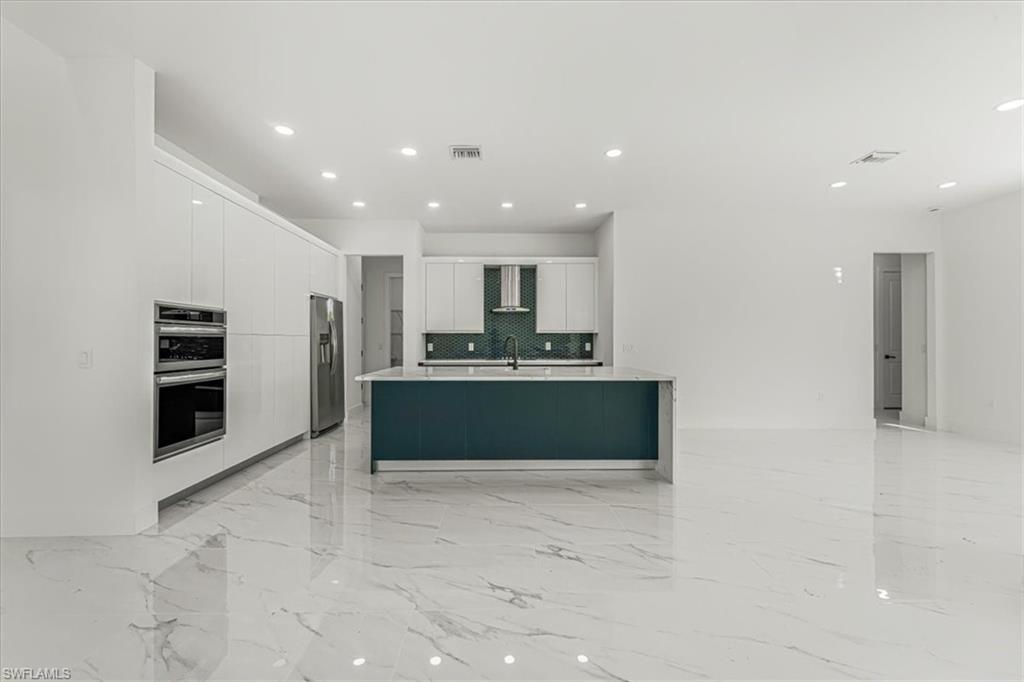 2941 37th Avenue Northeast Naples, FL 34120 - Photo 43 of 46 a large kitchen with stainless steel appliances kitchen island granite countertop a refrigerator and a sink