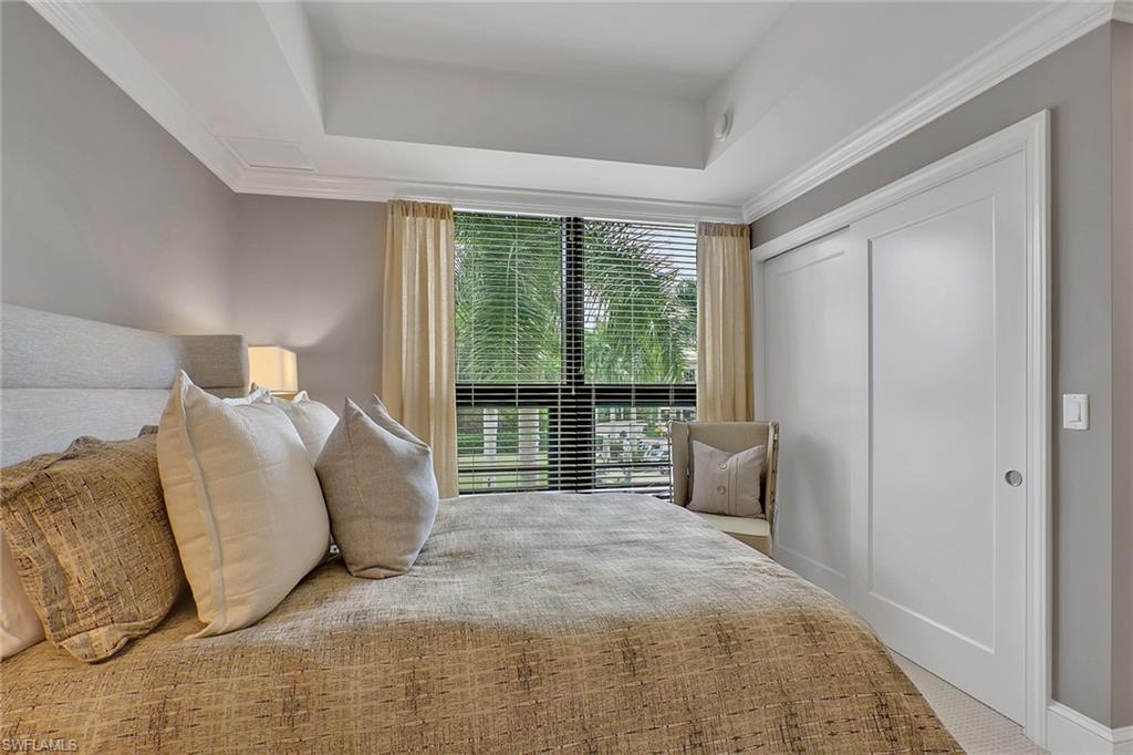 9123 Strada Place, Unit 7216 Naples, FL 34108 - Photo 14 of 28 Bedroom featuring a closet, a raised ceiling, carpet, and ornamental molding