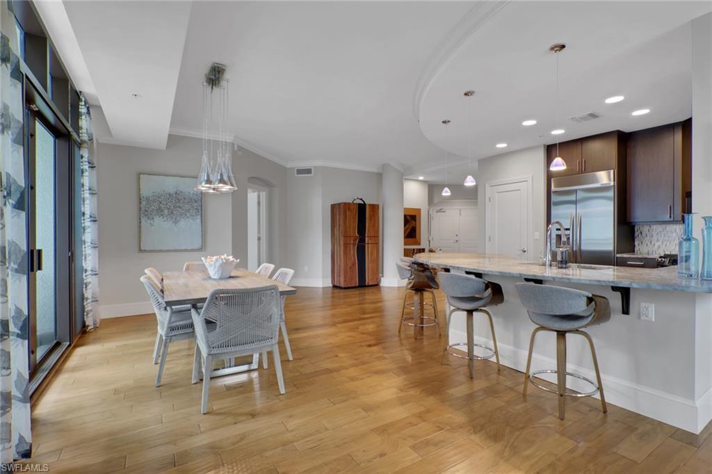9123 Strada Place, Unit 7216 Naples, FL 34108 - Photo 6 of 28 Kitchen with light stone counters, a breakfast bar, pendant lighting, a peninsula, and tasteful backsplash