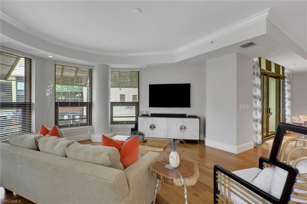 9123 Strada Place, Unit 7216 Naples, FL 34108 - Photo 8 of 28 Living area with ornamental molding, wood finished floors, and a raised ceiling