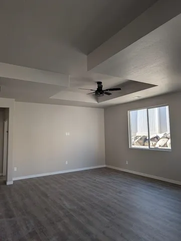 an empty room with wooden floor chandelier and windows