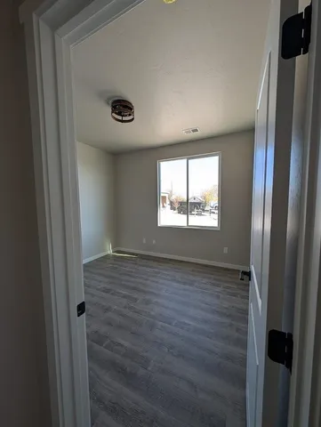 a view of an empty room with wooden floor and a window
