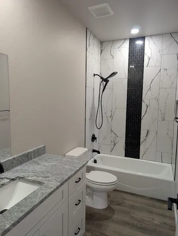 a bathroom with a granite countertop sink toilet and shower