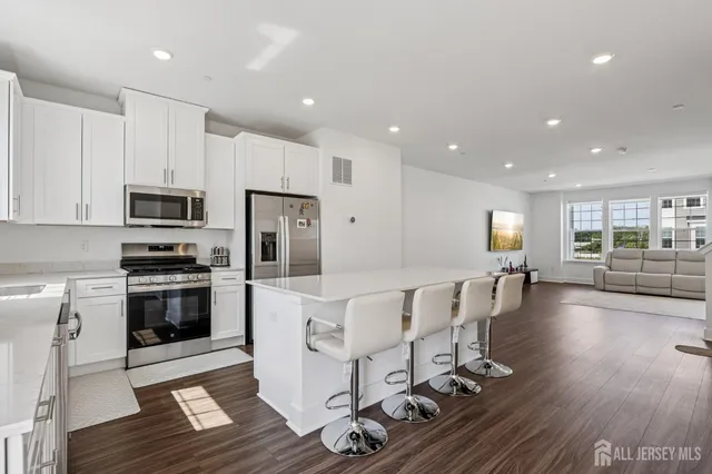 a living room with furniture wooden floor and a kitchen view