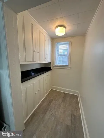 a view of an empty room with window and hardwood floor