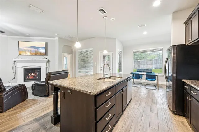 a kitchen with kitchen island granite countertop a stove a sink a center island and a wooden floor
