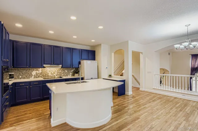 a kitchen with kitchen island granite countertop wooden floors and white cabinets