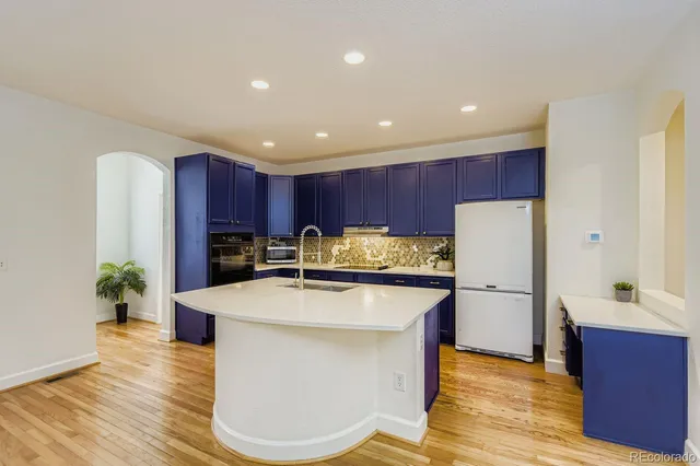 a kitchen with stainless steel appliances kitchen island granite countertop a refrigerator a stove and a wooden floors