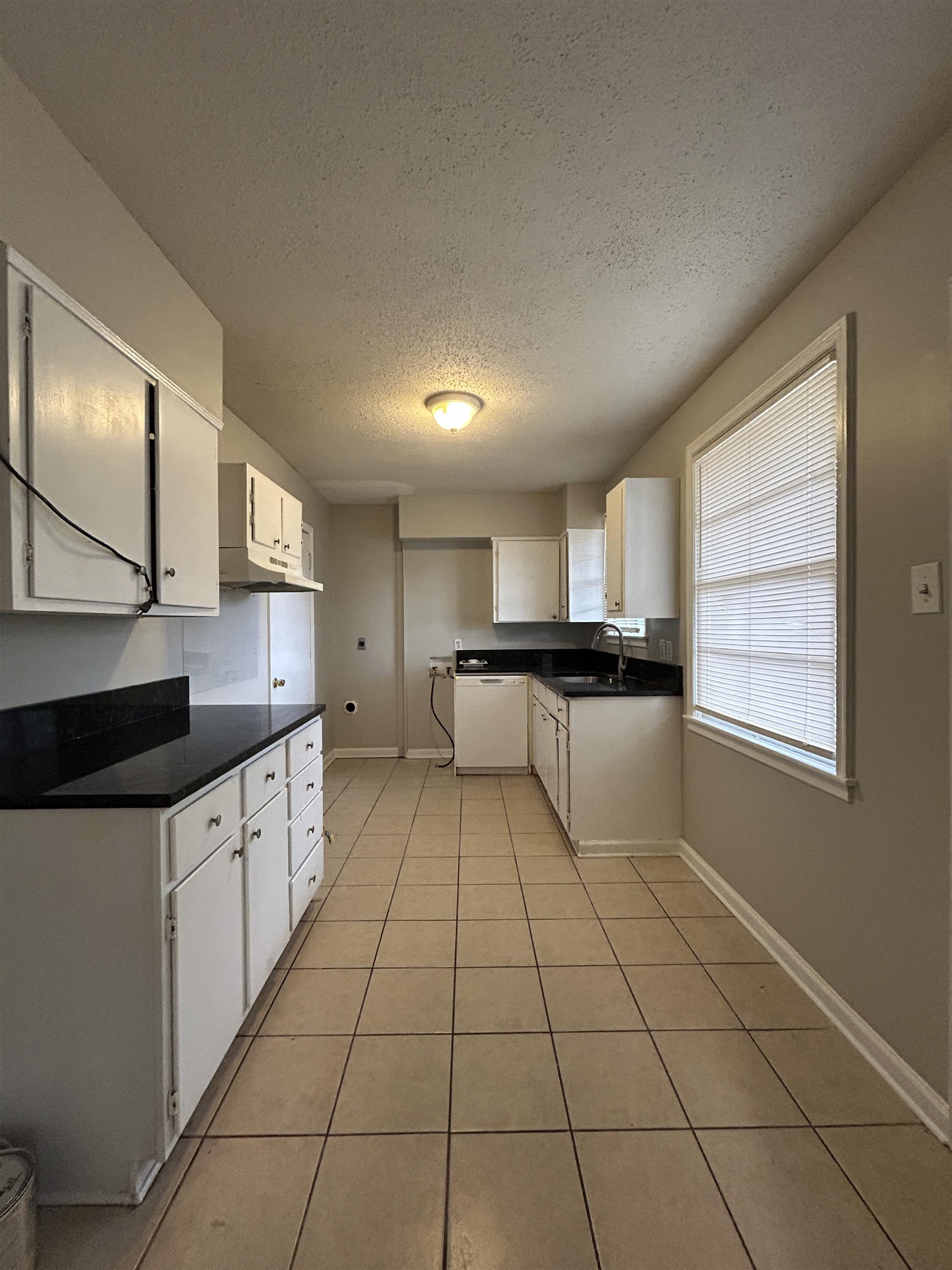 1809 Cherry Road Memphis, TN 38111 - Photo 5 of 16 Kitchen featuring white cabinets, a textured ceiling, dishwasher, light tile patterned flooring, and under cabinet range hood