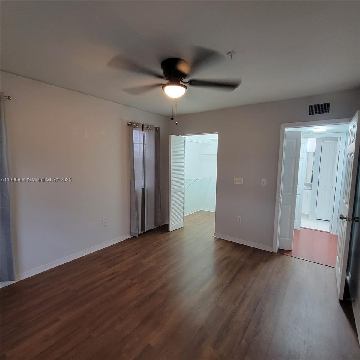 711 Southwest 111th Way, Unit 301 Pembroke Pines, FL 33025 - Photo 10 of 20 a view of an empty room with wooden floor and a ceiling fan