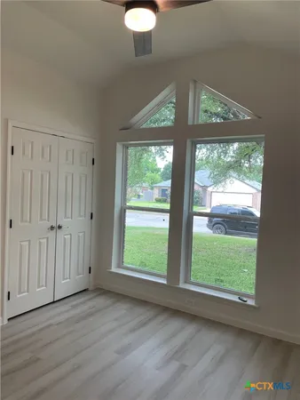 an empty room with wooden floor and windows