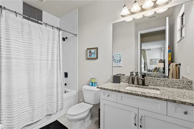 a bathroom with a granite countertop sink a toilet and a mirror