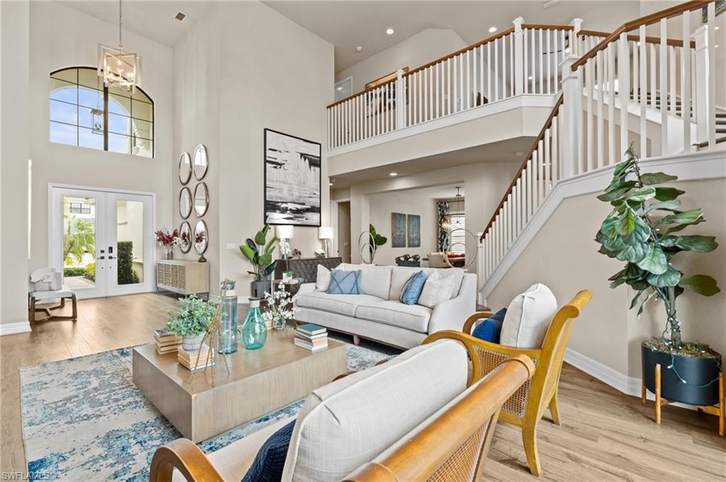 4644 Azalea Drive Naples, FL 34119 - Photo 5 of 48 a living room with couches a coffee table a chandelier and potted plants with wooden floor
