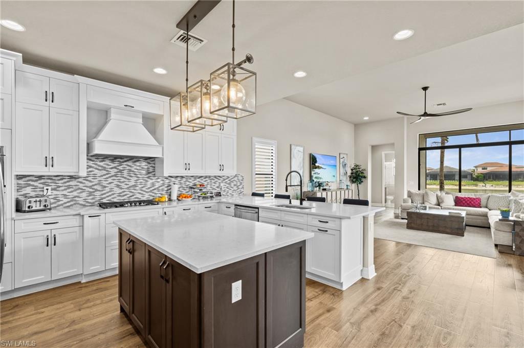 4644 Azalea Drive Naples, FL 34119 - Photo 7 of 48 a kitchen that has a lot of cabinets a sink a stove and wooden floor