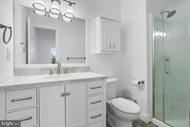 a bathroom with a granite countertop sink a toilet and a mirror