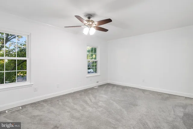 an empty room with windows and fan