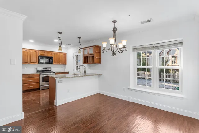 a kitchen with stainless steel appliances kitchen island granite countertop a stove a sink dishwasher a refrigerator and a dining table with wooden floor