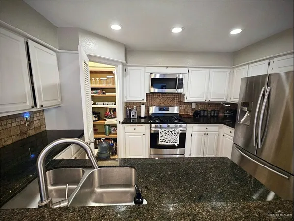 a kitchen with stainless steel appliances granite countertop a refrigerator sink and stove