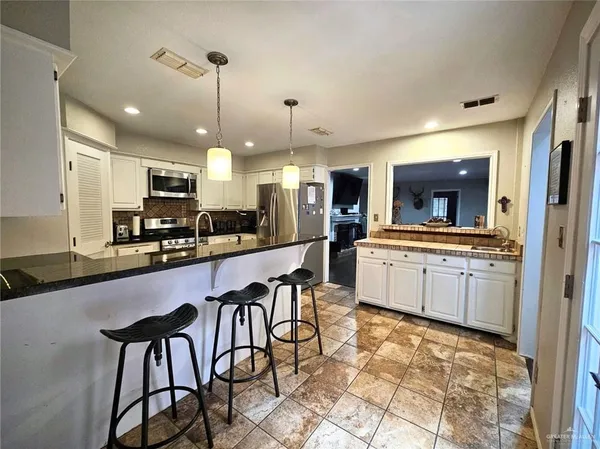 a large kitchen with granite countertop lots of counter space dining table and stainless steel appliances