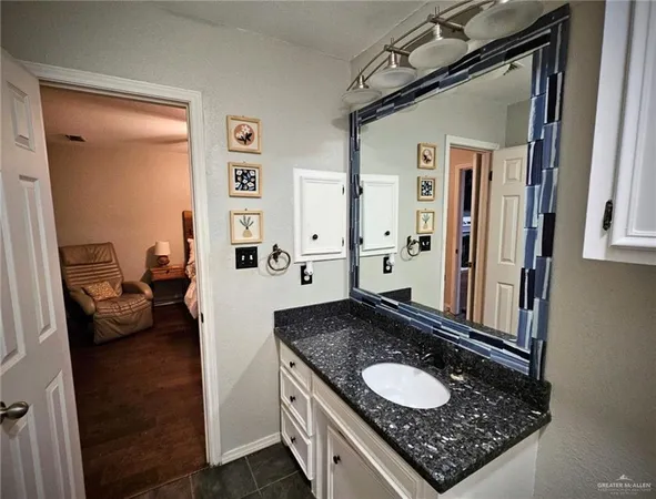 a bathroom with a granite countertop sink and a mirror