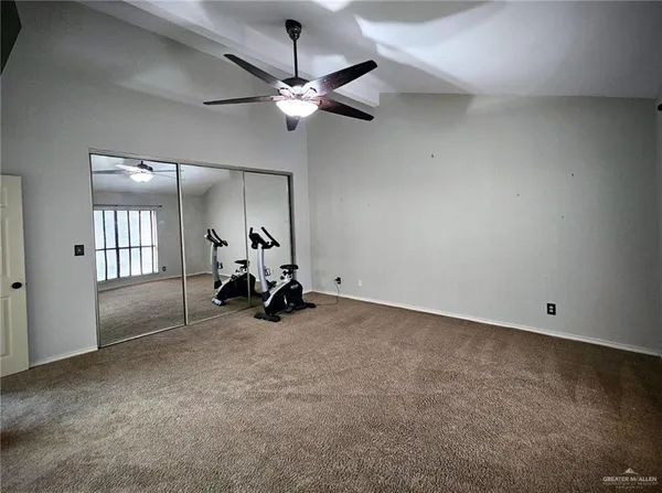 an empty room with chandelier fan and windows