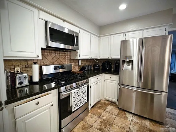 a kitchen with granite countertop a refrigerator stove and microwave