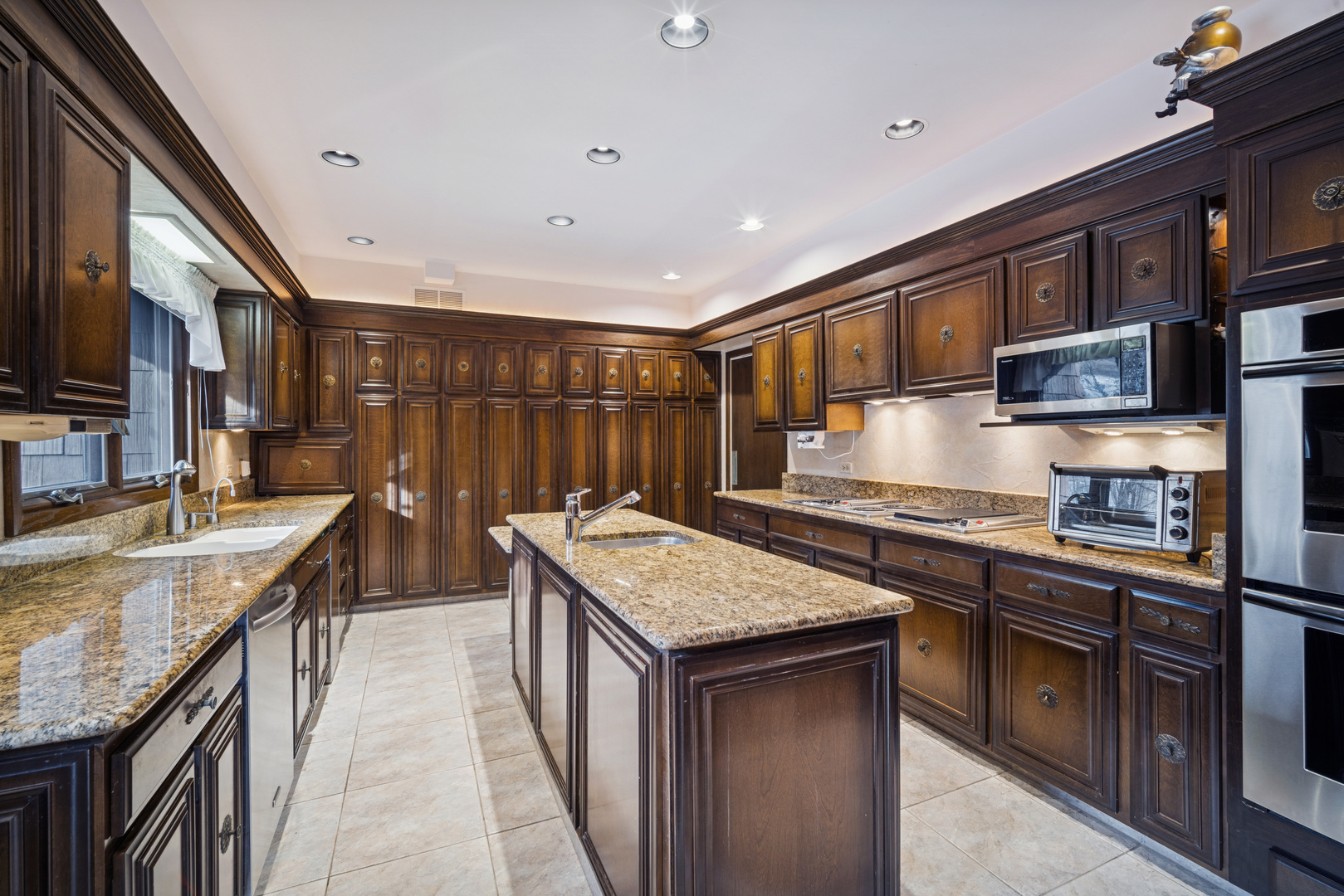 990 Heather Road Deerfield, IL 60015 - Photo 12 of 28 a kitchen with stainless steel appliances granite countertop sink stove top oven and cabinets