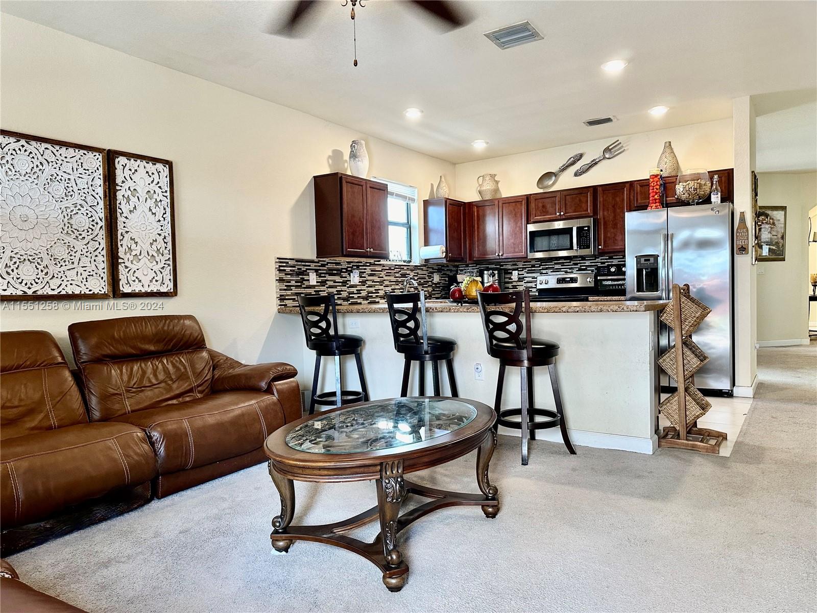 24162 Southwest 115th Court Homestead, FL 33032 - Photo 3 of 8 a living room with stainless steel appliances furniture a kitchen view and a flat screen tv