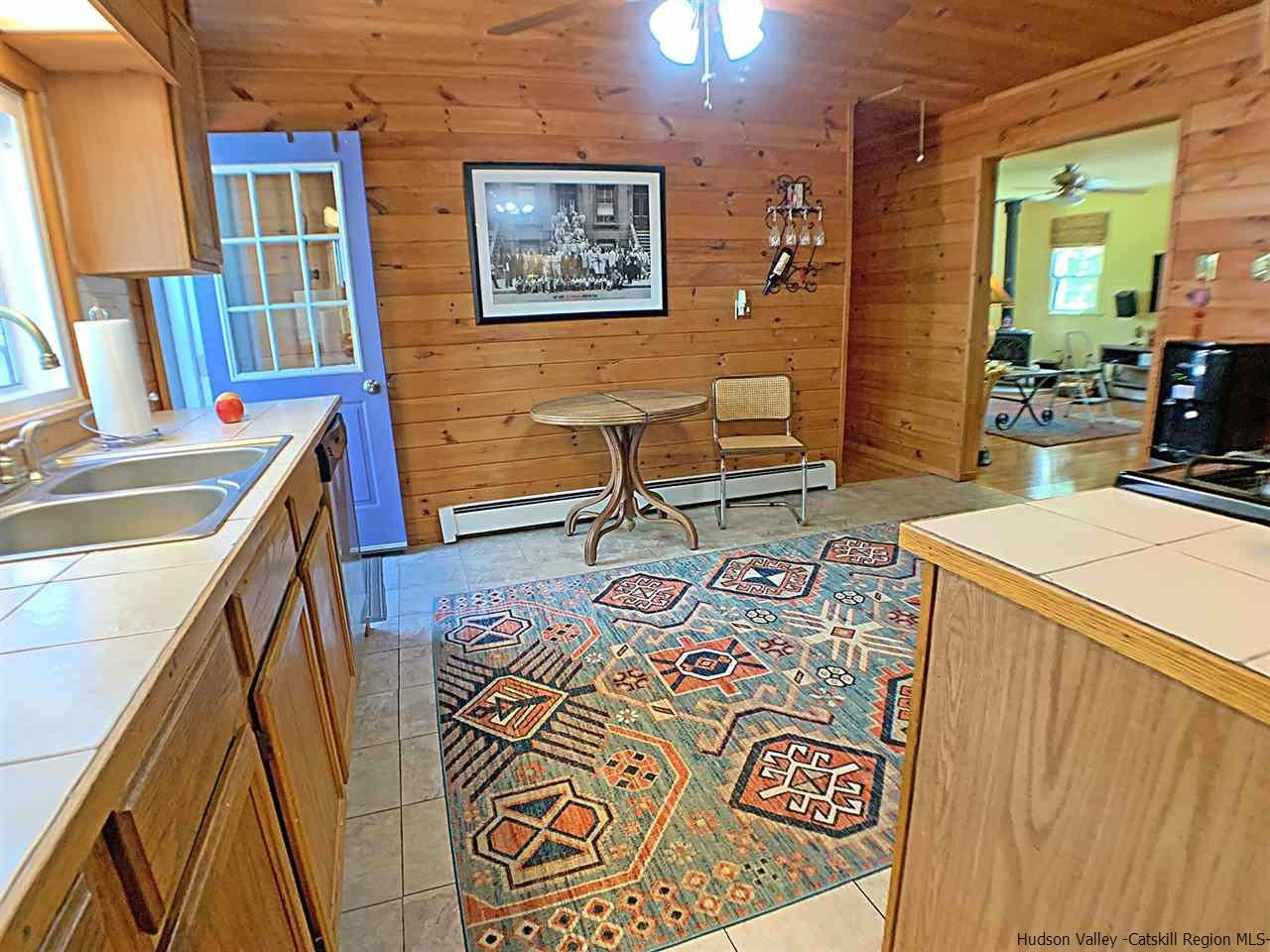 56 Bellwood Road Saugerties, NY 12477 - Photo 12 of 35 a living room with a couch and a dining table with wooden floor
